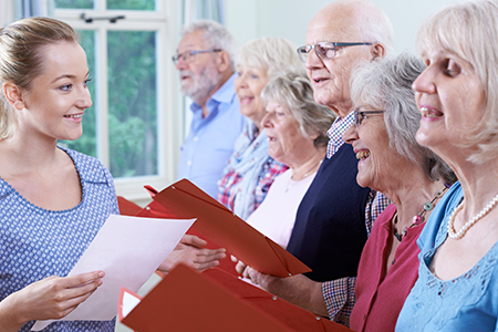 A group singing together with song sheets in hand