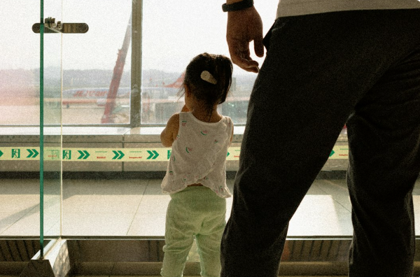 Child and adult looking through airport window